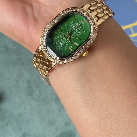A gold-tone wristwatch with a green sunburst dial and a rhinestone-studded bezel, shown worn on a person's wrist.